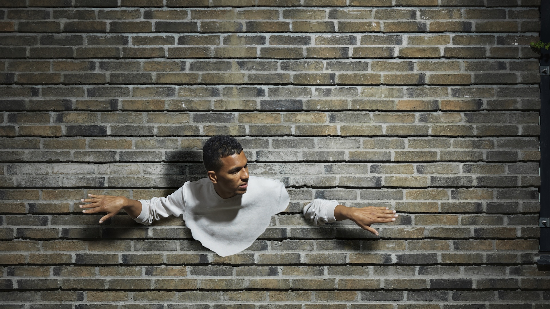 an edited photo of a man appearing to walk through a brick wall
