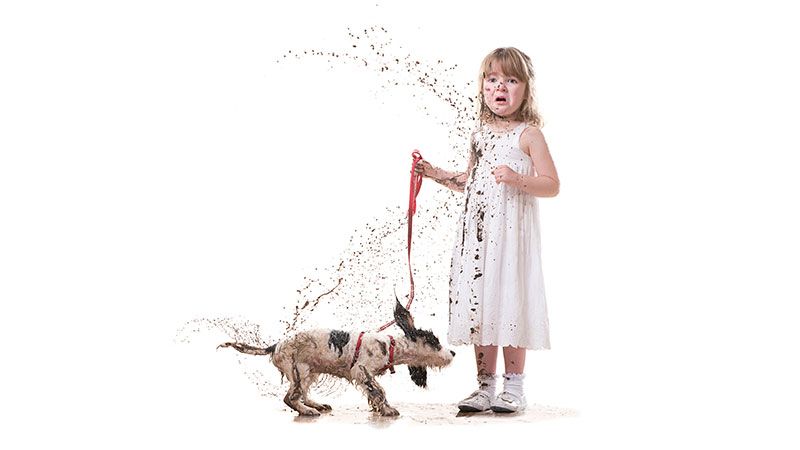 Dog shaking dirty water over girl