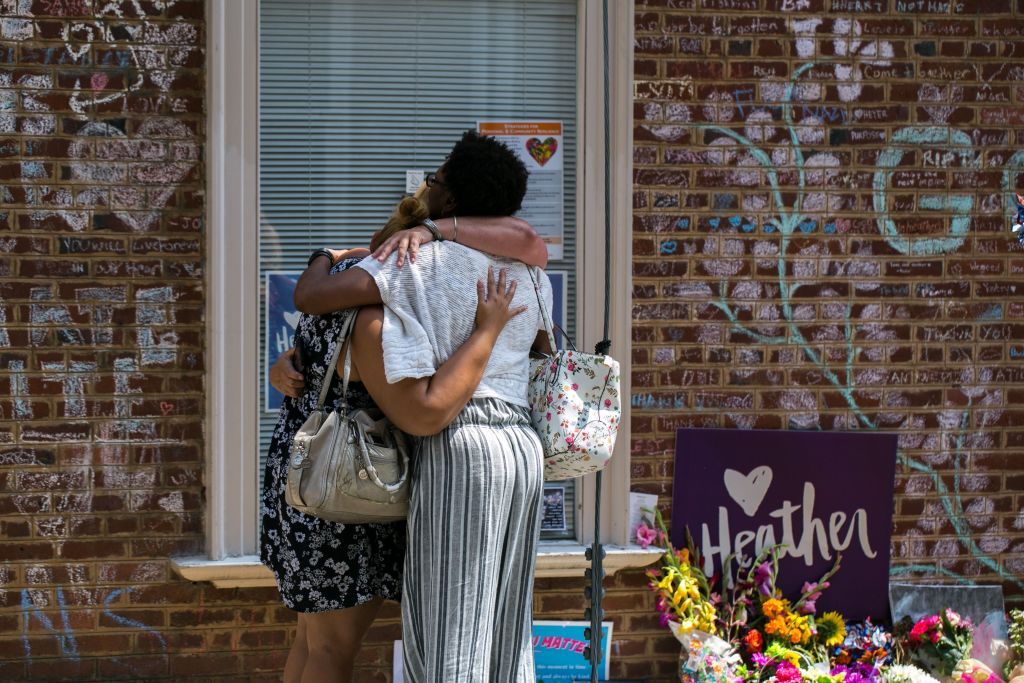 Mourners embrace in front of the hand-written chalk messages that line the walls outside the buildings where one year ago Heather Heyer was killed by a speeding vehicle driven by a white supr