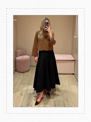 Eliza Huber in the dressing room at Me+Em's new NYC store wearing a brown leather jacket and black skirt.