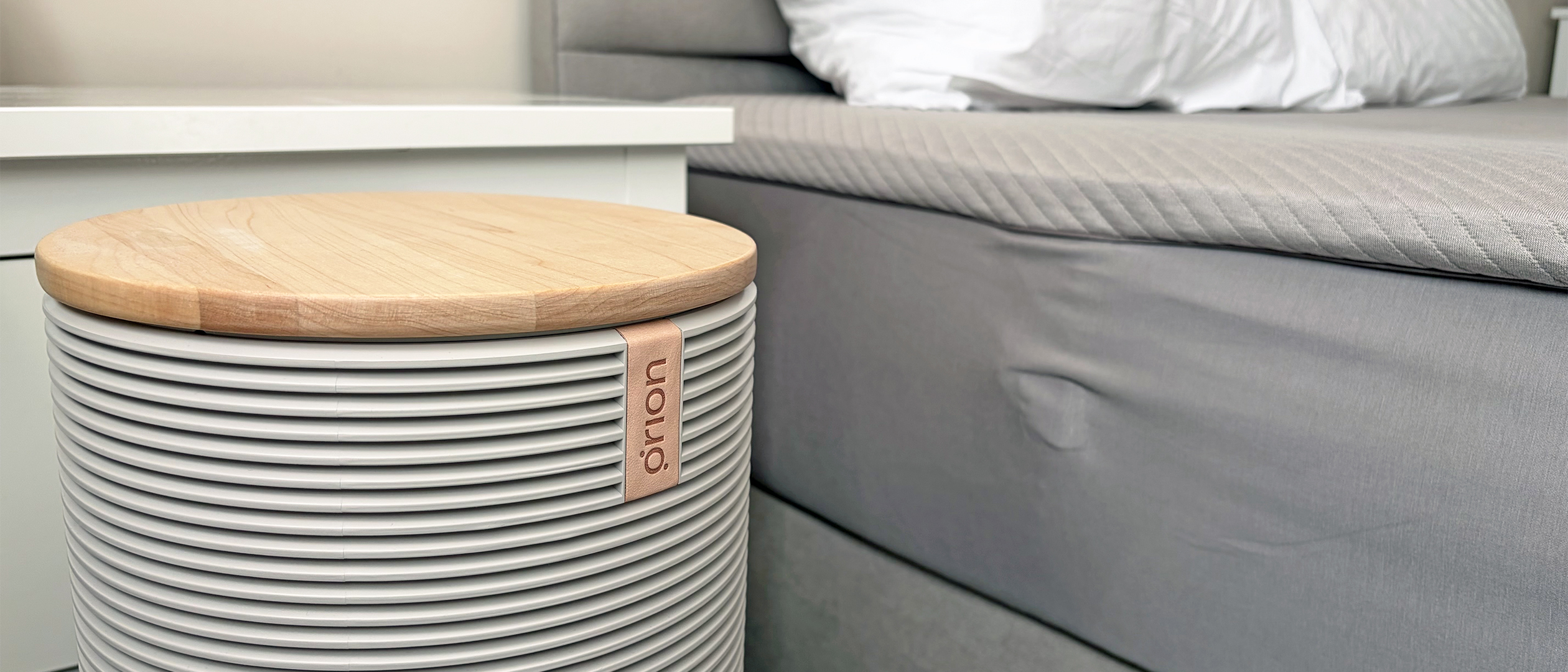 A close up of the Orion Sleep System Control tower next to the Orion mattress cover on a bed in our reviewer's bedroom