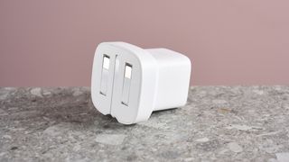 Anker 323 Charger (33W) balanced on its side against a pink background