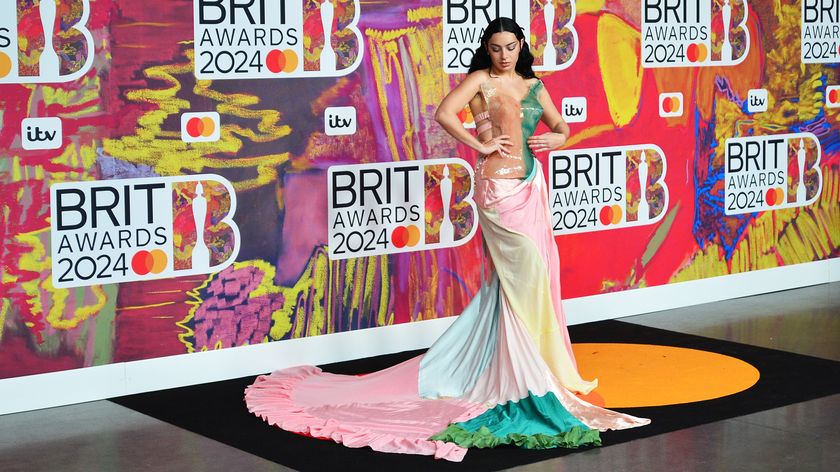 Charli XCX on the red carpet of the Brit Awards 2024 wearing a long colorful dress