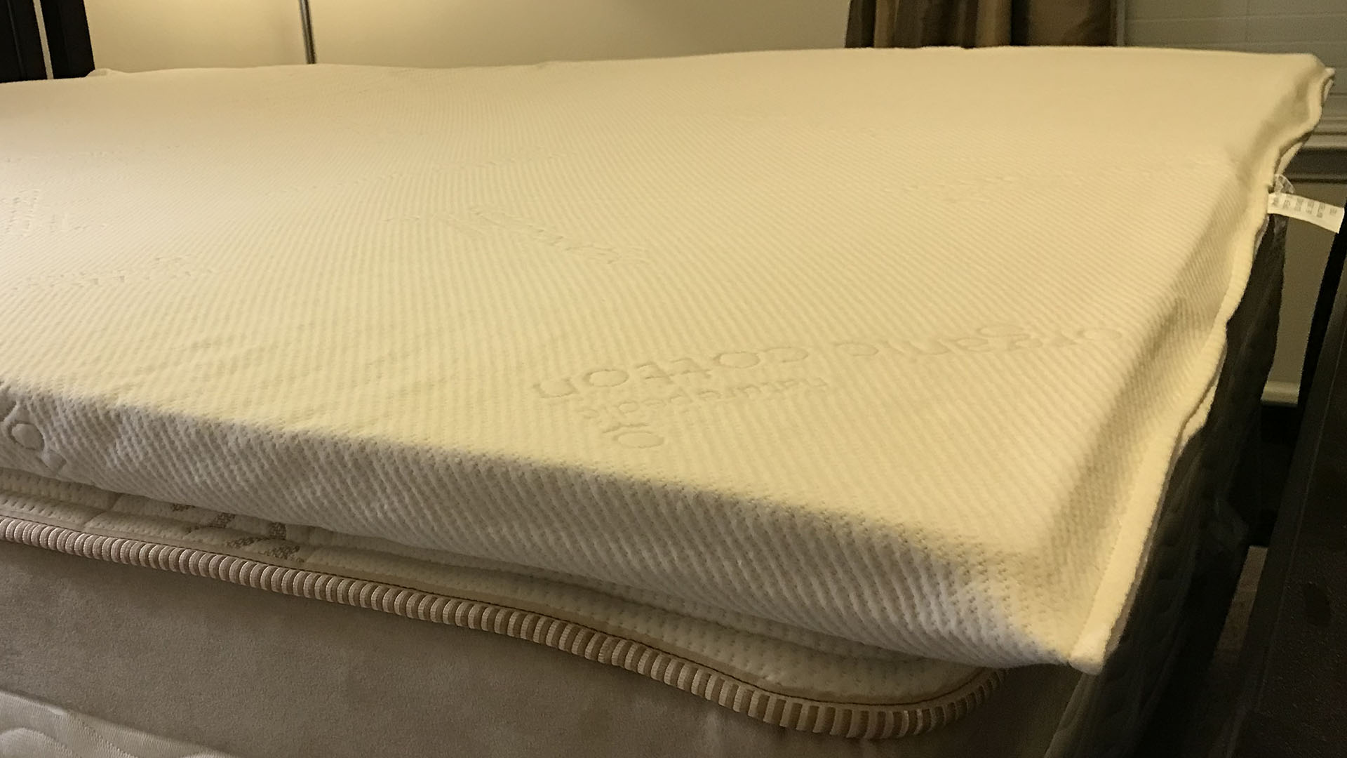 Naturepedic Adagio latex mattress topper on a bed