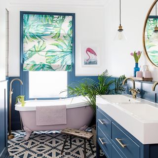 bathroom with pink bath, blue vanity unit and palm print blind