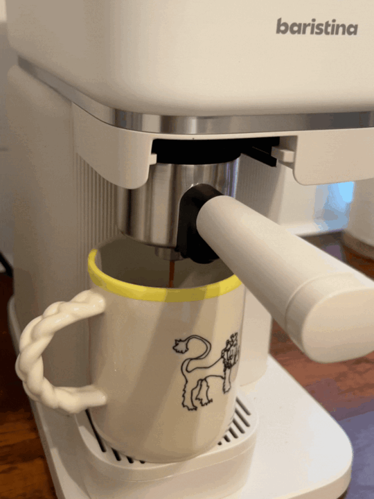 GIF of an espresso shot being brewed from a white coffee maker into a white coffee mug.