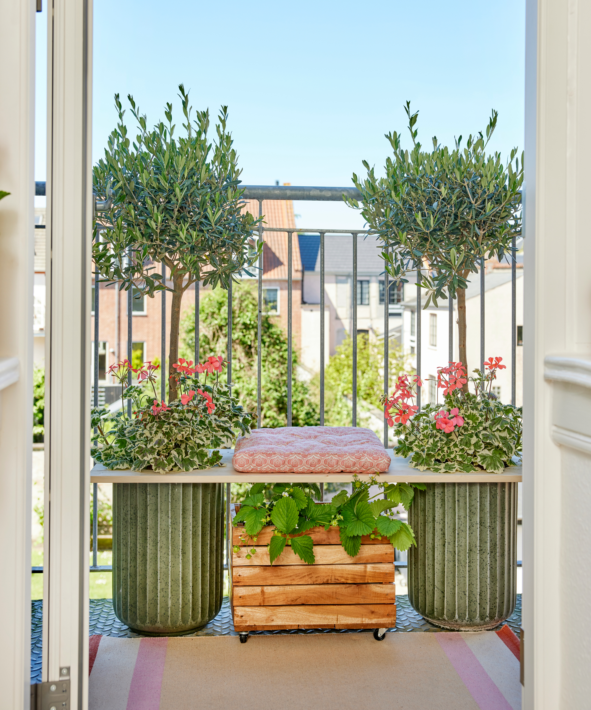 DIY bench made from wooden plank and two large containers on a balcony