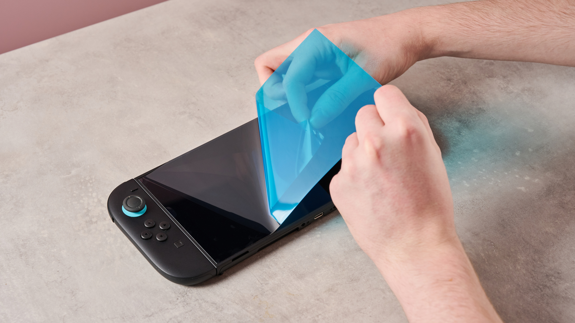 Person applying screen protector from the Nintendo Switch 2 Carrying Case &amp;amp; Screen Protector package