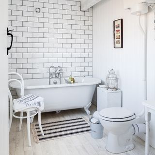 bathroom with white tiled walls wooden flooring and white bathtub