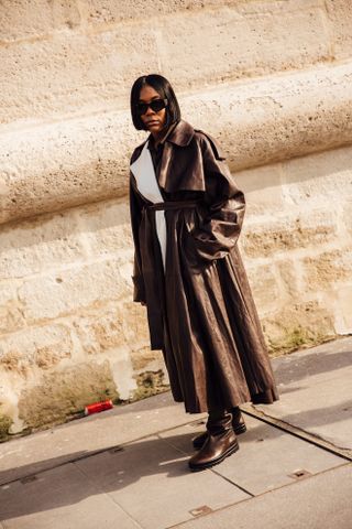 woman wearing leather trench coat, white dress, and brown boots