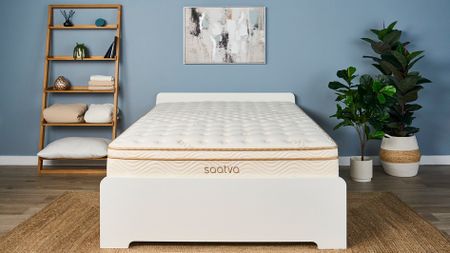 The Saatva Classic luxury innerspring hybrid is the best mattress we've tested, scoring 4.8 out of 5 in our seven robust data-led lab tests and value for money analysis. Here it's photographed on a white wooden bed frame in our blue coloured sleep product testing lab