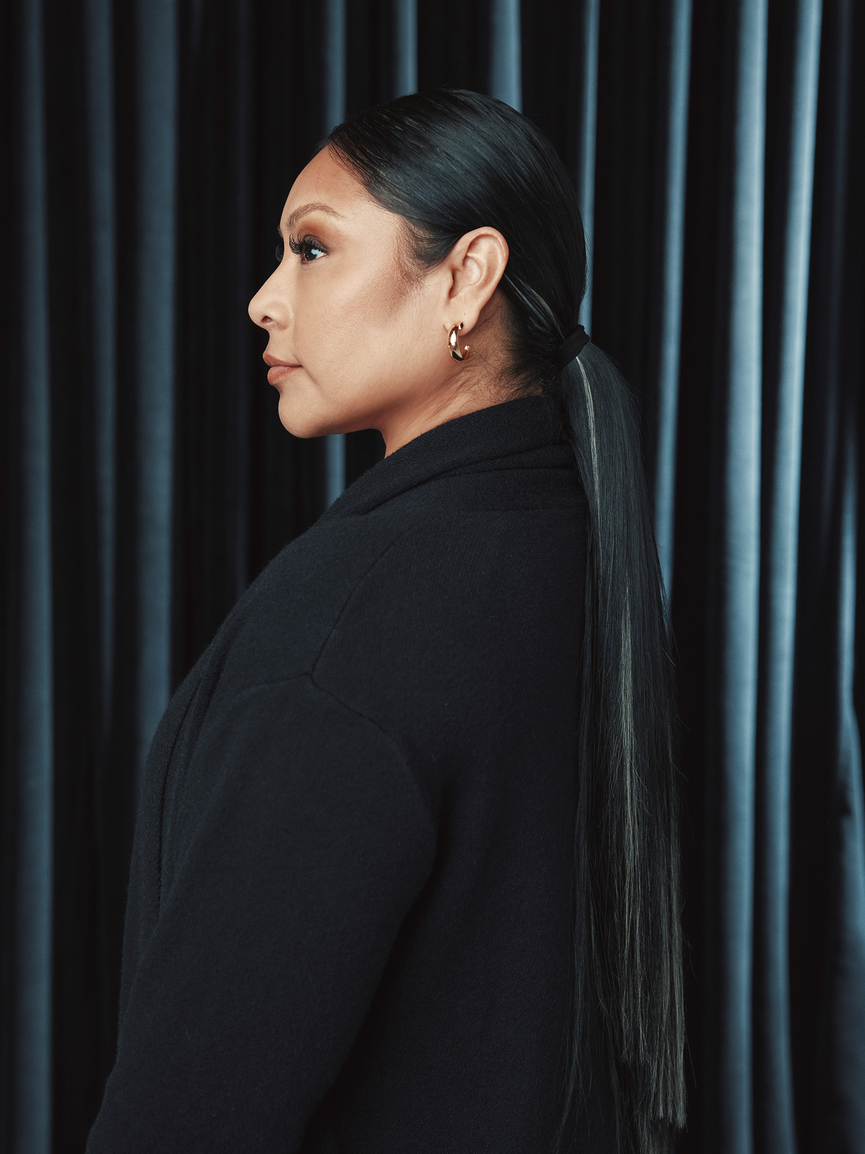 Side-profile portrait of Angelica Vargas in a dark jacket with a long ponytail.