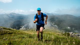 Man wearing sports watch running alone mountain ridge