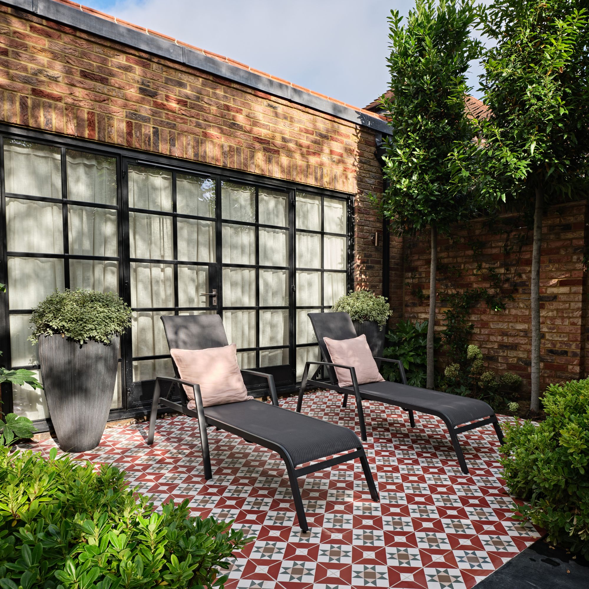 A garden seating zone with red and white tiled details underneath