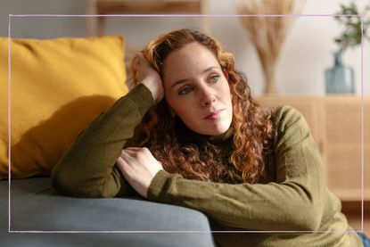 Woman leaning against sofa looking thoughtful