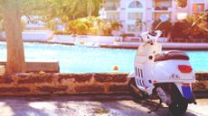 White scooter parked by the waterside - a popular mode of transport in nations like Bermuda.