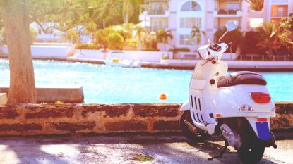 White scooter parked by the waterside - a popular mode of transport in nations like Bermuda.