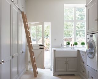 A light utility room with tall cupboards and a wooden ladder.