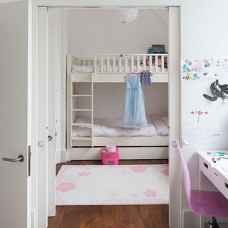 kids bedroom with white wall bunk bed white door and wooden flooring