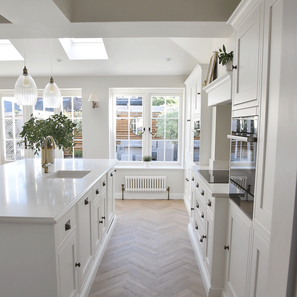 White kitchen with lots of counters, an island and gold tap