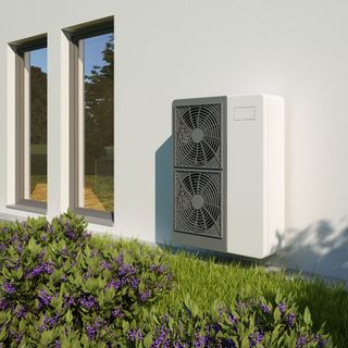 White and grey heat pump on the side of a white house