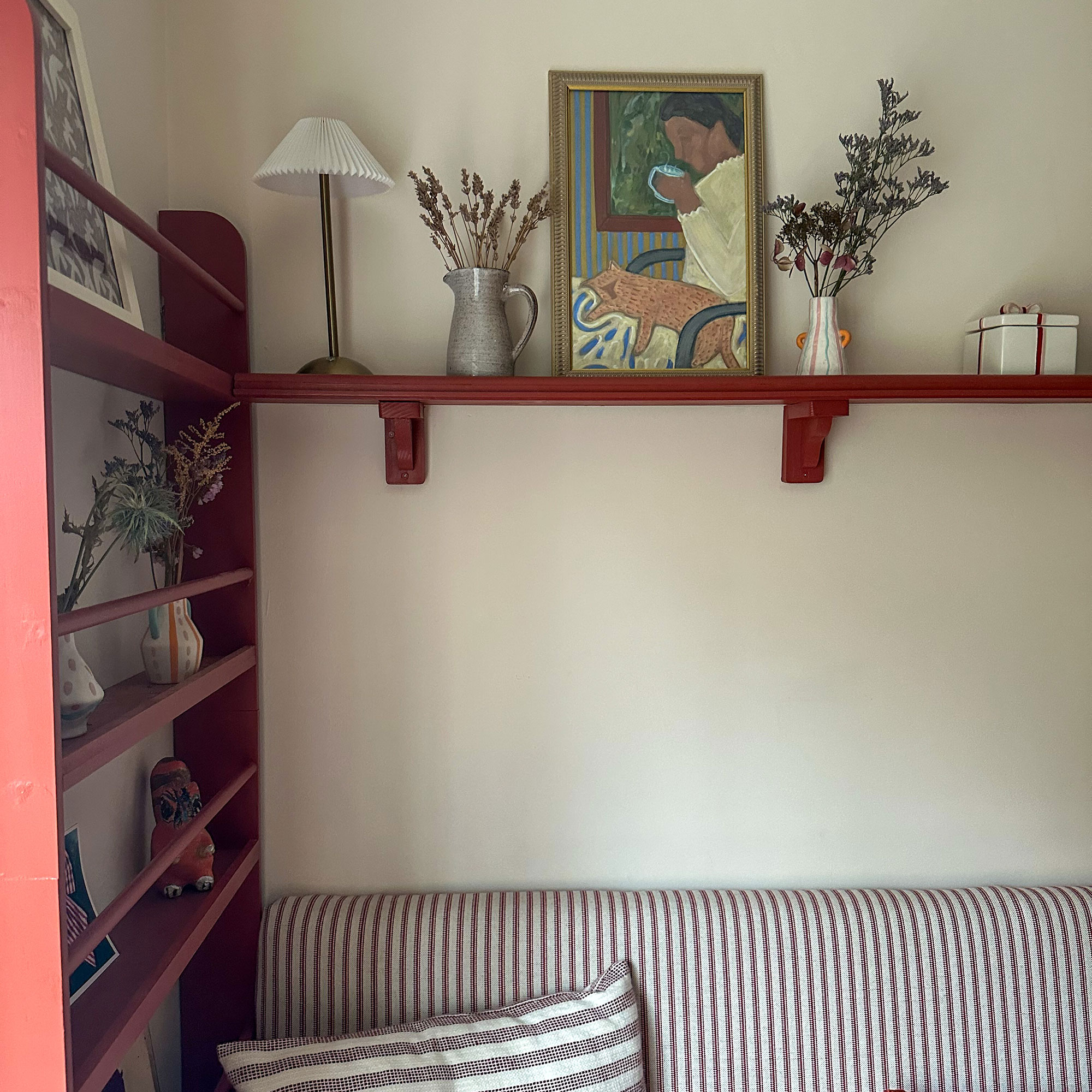 Corner of kitchen with red shelving and striped upholstered seating