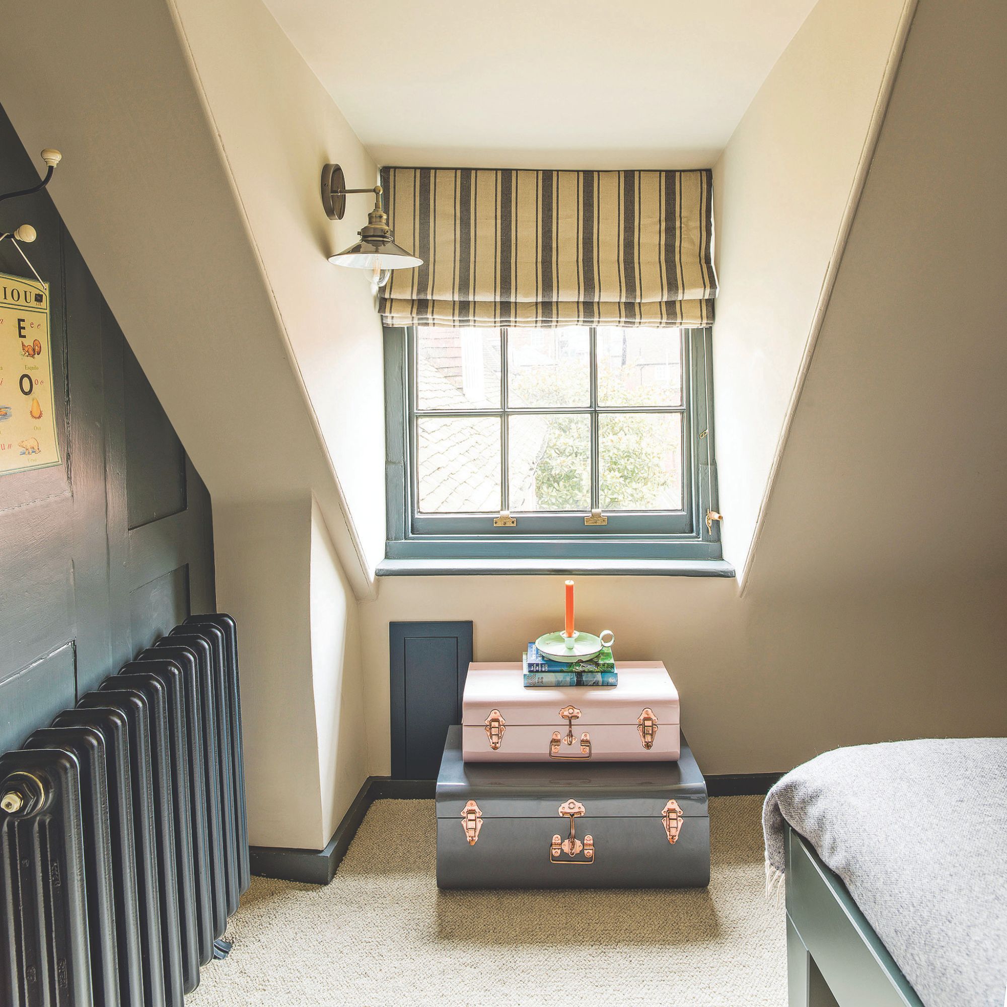 Beige painted loft bedroom with two decorative trunks sitting underneath a window with blue painted frames