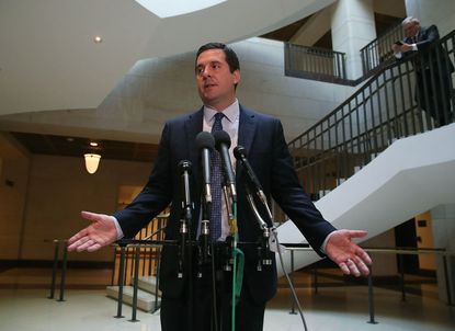 Devin Nunes stands in front of microphones, his hands outstretched.