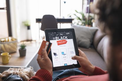 A person shopping a Black Friday sale on his ipad with his credit card in hand.