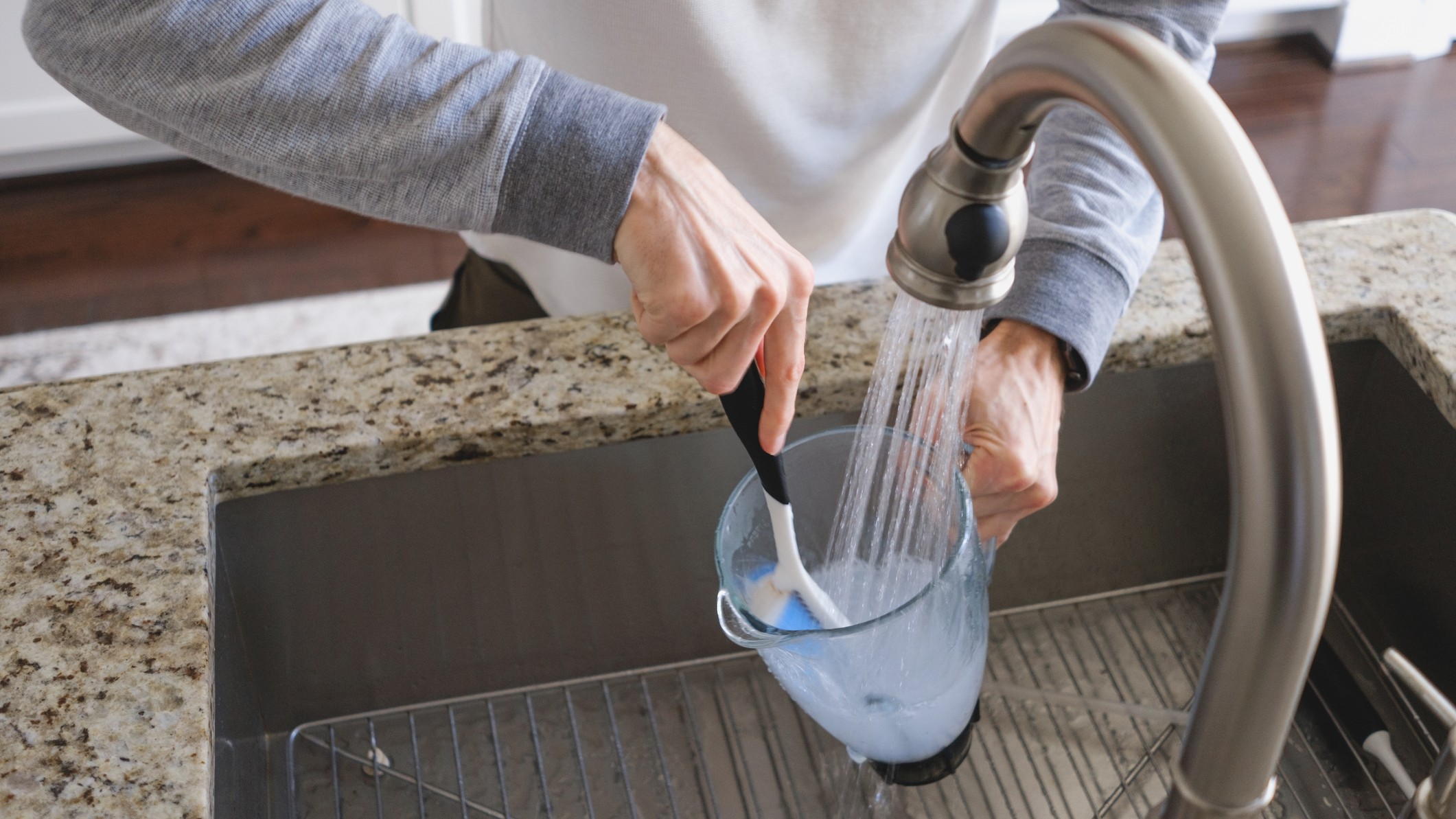 Person washing blender jug in sink
