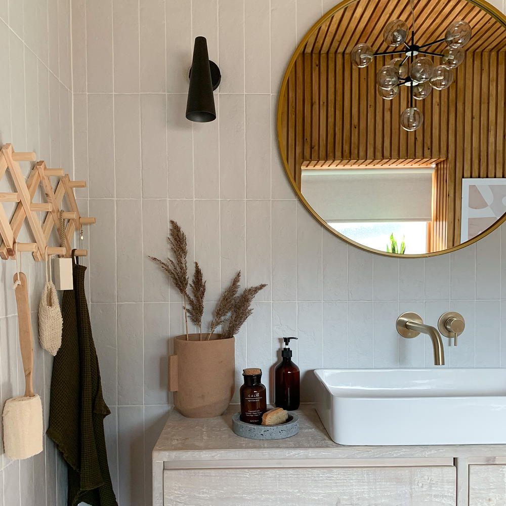bathroom with white tiles on wall round mirror and white washbasin