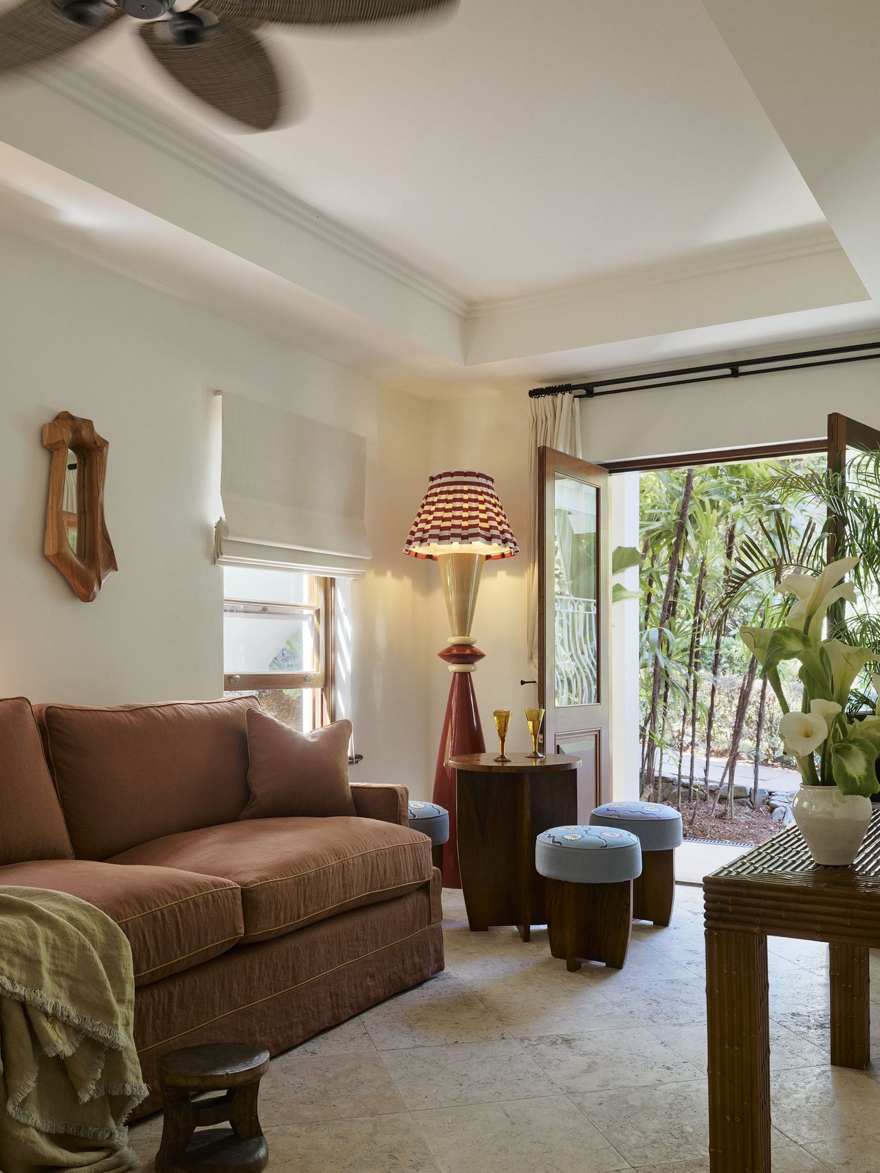 A seating area with French doors leading to the outdoor area featuring an orange sofa and red striped lamp