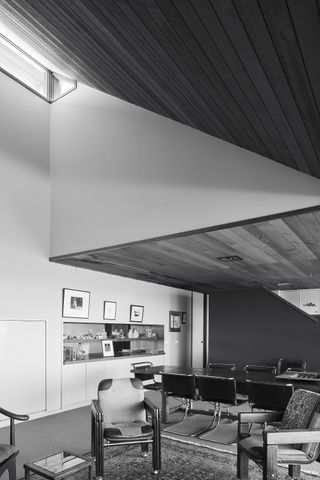 Another of his projects, Wanniassa House, is located in the namesake suburb of Canberra. A meeting room with a long table and chairs in front of a sitting area with chairs and a square coffee table.