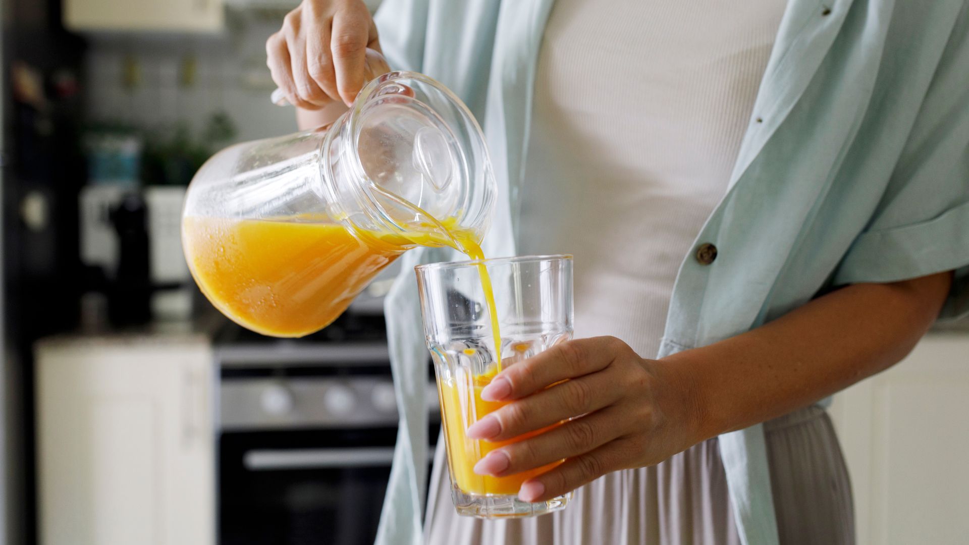 5 foods that cause bloating - woman pouring orange juice