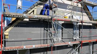 scaffolded exterior of house with exterior wall insulation being added