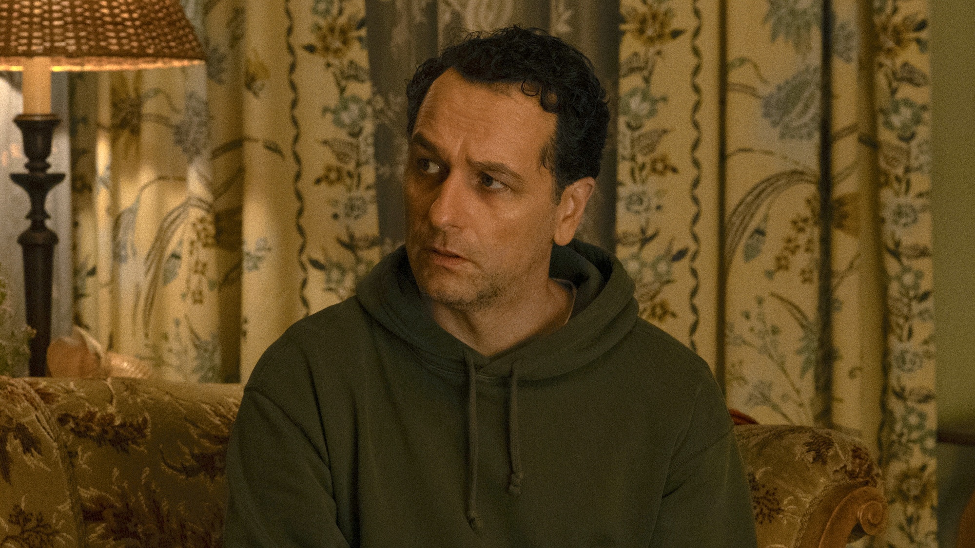 Tom sitting on Ruth's old school couch in Widow's Bay Season 1 finale