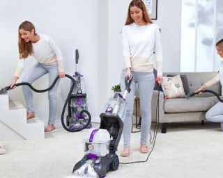 VAX Rapid Power Refresh CDCW-RPXR Upright Carpet Cleaner in use by woman in three ways - on stairs, on sofa and on carpet