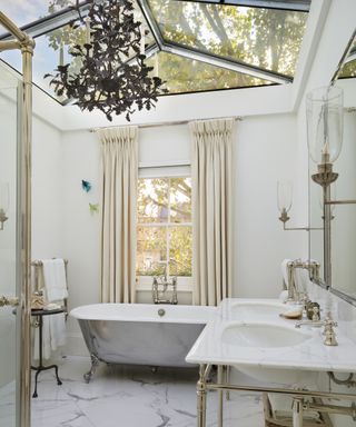 A white bathroom with black chandelier and glass ceiling