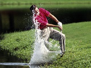 Male golfer hitting a difficult golf shot near the water