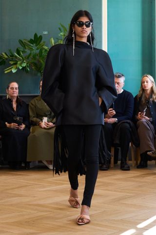 model wears a Leggings outfits of black leggings, black top, heels, and silver earrings.