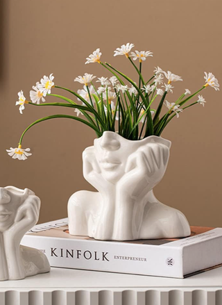 bust vase with a head leaning on cupped hands and shoulders with daisies coming out of the head