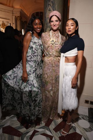 A photo of Ayo Edebiri, Greta Lee, and Hari Nef posing together at the Business of Fashion party