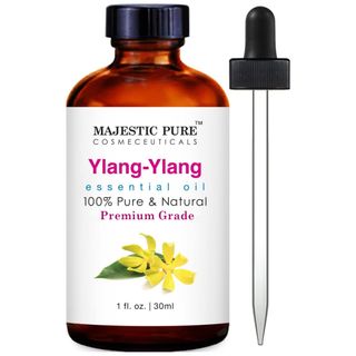 A brown glass bottle of Ylang-Ylang essential oil with a white label with Ylang-Ylang flower and blue, pink and black text, and pipette with black lid