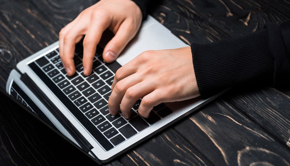 Hands typing on a laptop keyboard.