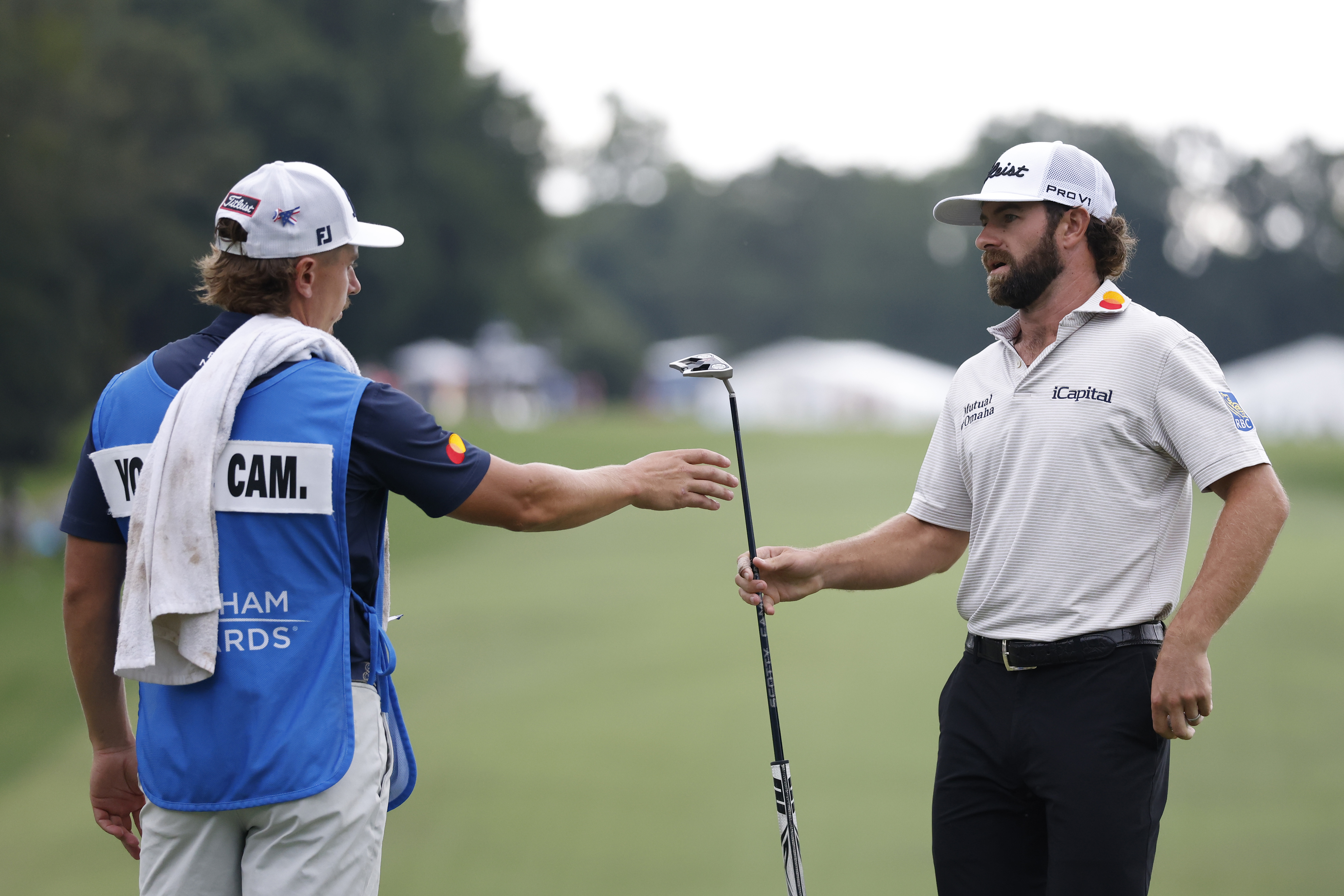 Cameron Young hands his putter to his caddie