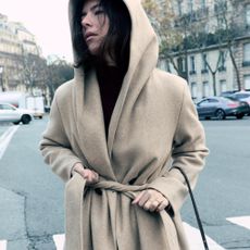 A model wearing an elegant hooded coat from Zara.