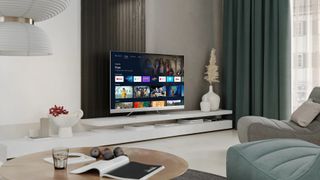 Sharp EQ - Et sharp fjernsyn med tændt skærm står på en tv-reol i en lys stue