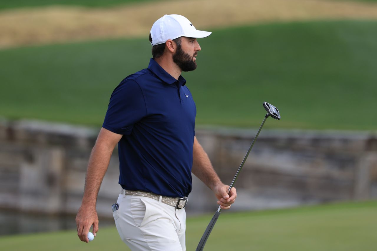 Scottie Scheffler walks off the green holding a putter