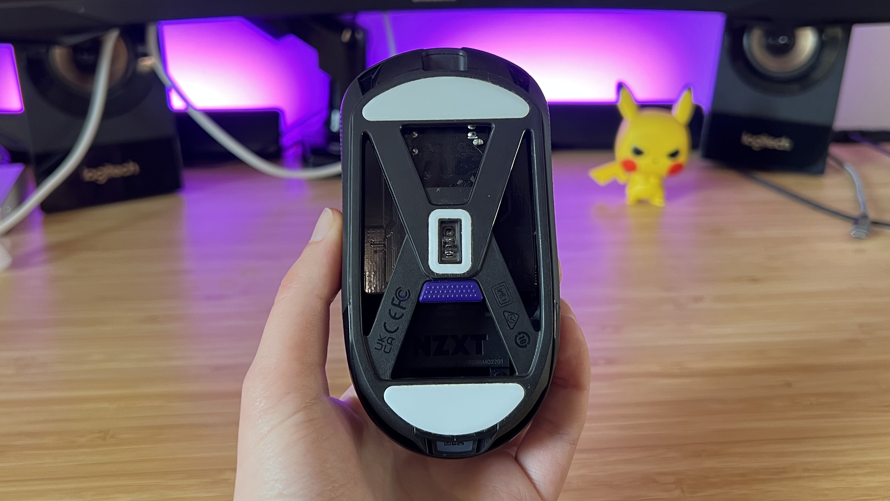 Hand holding NZXT Lift Elite Wireless gaming mouse showing hollowed out underside and DPI shifting button