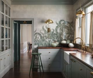 A white and green kitchen with a tile mural backsplash taken up to the ceiling